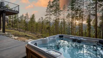 a hot tub on a deck with a view of a forest at Vickerys Vantage in Breckenridge