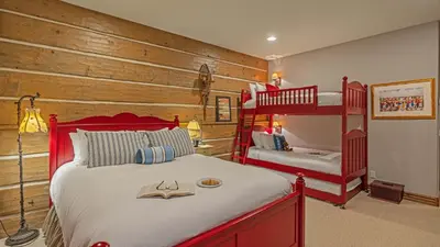 a bedroom with a red bed and bunk beds at Cypress Mountain Chalet in Breckenridge