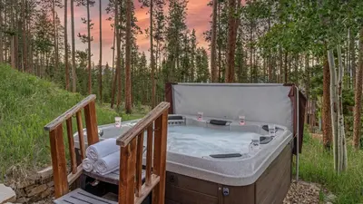 a bath tub sitting on a deck in the woods at Cypress Mountain Chalet in Breckenridge