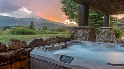 a hot tub in a stone wall with the sunset at Monte Video in Breckenridge