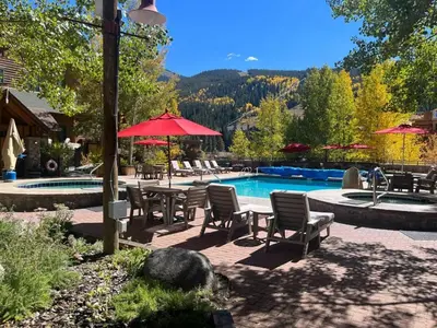 a swimming pool with chairs and umbrellas and a table and a swimming pool at 4BD Family Friendly Minutes from River Run Gondola in Keystone