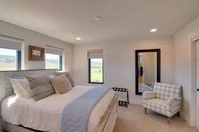 a bedroom with a bed and a chair and windows at Colorado Home with Hot Tub! Close to Ski Resorts in Granby
