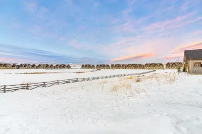 a snow covered field with a house and a fence at Colorado Home with Hot Tub! Close to Ski Resorts in Granby
