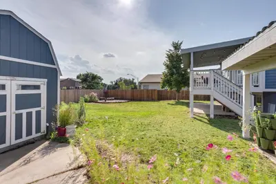 a backyard with a yard of grass and flowers at Furnished Deck and Fire Pit Thornton Family Retreat in Thornton