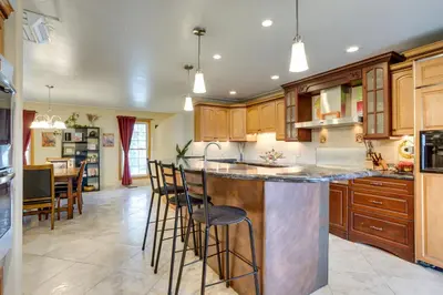 a kitchen with wooden cabinets and a island with bar stools at Furnished Deck and Fire Pit Thornton Family Retreat in Thornton