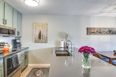 a kitchen with a vase of flowers on a counter at Elevated Fraser Condo with Mountain View and Amenities in Fraser