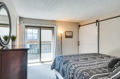 a bedroom with a bed and a mirror and a window at Elevated Fraser Condo with Mountain View and Amenities in Fraser