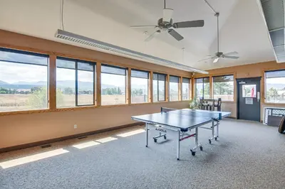 an empty room with a ping pong table and windows at Elevated Fraser Condo with Mountain View and Amenities in Fraser