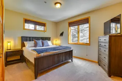 a bedroom with a bed and a dresser and windows at Walk to Main Street Grand Lake Condo with Patio in Grand Lake