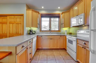 a kitchen with wooden cabinets and white appliances at Walk to Main Street Grand Lake Condo with Patio in Grand Lake