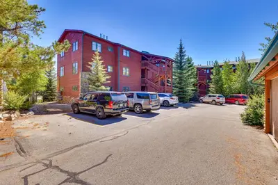 a parking lot with cars parked in front of a building at Walk to Main Street Grand Lake Condo with Patio in Grand Lake