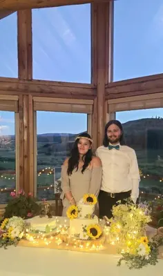 a man and woman standing next to a table with a cake at Wapiti Retreat at 22 West Cabins and Recreation in Walden