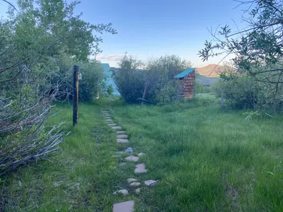 a path in a field with a pole in the grass at Red-tail Roundhouse at 22 West Cabins and Recreation in Hebron