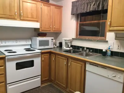 a kitchen with white appliances and wooden cabinets at Whistle Pig Retreat at 22 West Cabins and Recreation in Hebron