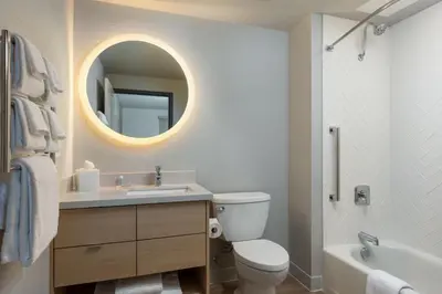 a bathroom with a toilet and a sink and a mirror at TownePlace Suites by Marriott Denver North Thornton in Thornton