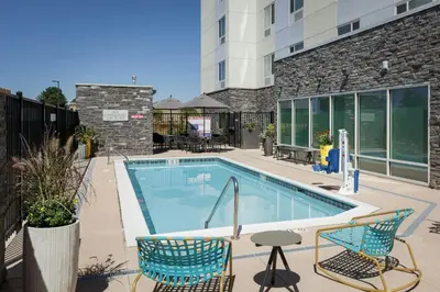a swimming pool with two chairs next to a building at TownePlace Suites by Marriott Denver North Thornton in Thornton
