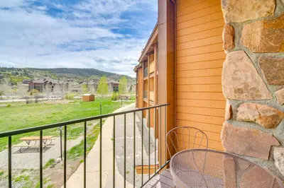 a balcony with two chairs and a stone wall at 2 Mi to Granby Ranch Mtn Condo with Hot Tub! in Granby