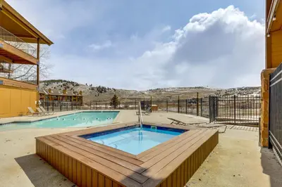 a swimming pool with a wooden deck next to a building at 2 Mi to Granby Ranch Mtn Condo with Hot Tub! in Granby