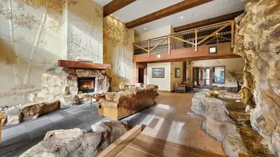 a large living room with a large stone fireplace at Ski in Ski out 1 BDR at River Run Village in Keystone