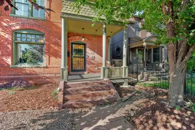 a brick house with a porch and a tree at 151 W 2nd Ave - Denver in Denver