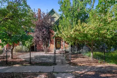 a fence in front of a house with trees at 151 W 2nd Ave - Denver in Denver