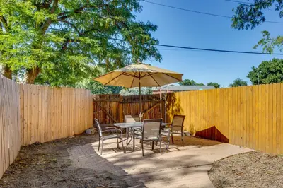 a table and chairs with an umbrella and a fence at 9 Mi to Dtwn Denver Aurora Vacation Rental in Aurora
