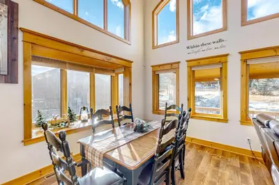 a dining room with a wooden table and windows at Moose Cabin in Grand Lake