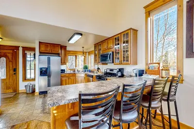 a kitchen with wooden cabinets and a island with bar chairs at Moose Cabin in Grand Lake