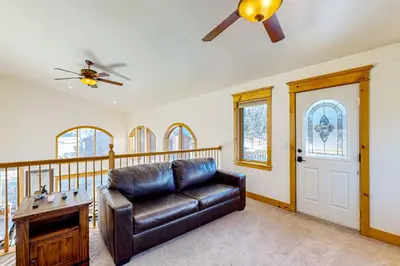 a living room with a leather couch and a ceiling fan at Moose Cabin in Grand Lake