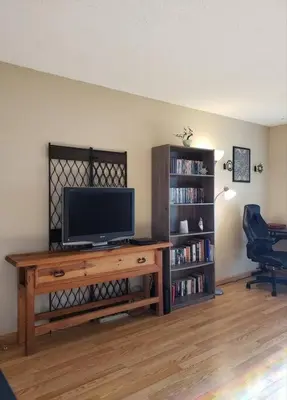 a living room with a television and a book shelf at Entire 1 BR Condo- Near Anschutz, UC Health, DIA- In-Unit Washer Dryer- Seasonal Discounts! in Aurora