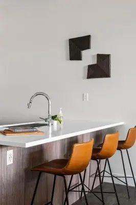 a kitchen with orange chairs at a counter at Polished Stayscape | Espadin LoHi in Denver