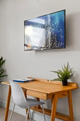 a wooden desk with a television on a wall at Polished Stayscape | Espadin LoHi in Denver