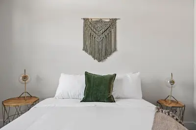 a bedroom with a bed with white sheets and green pillows at Polished Stayscape | Espadin LoHi in Denver
