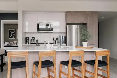 a kitchen with a counter with four chairs around it at Rhythm of Night | Espadin LoHi in Denver