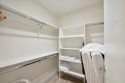 a walk in closet with white cabinets and a mirror at Natural Influence | Espadin LoHi in Denver