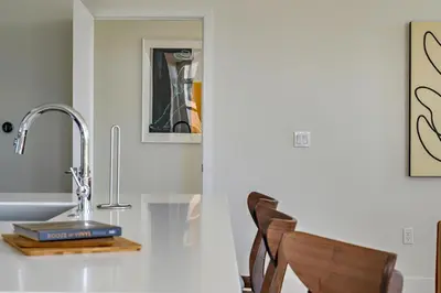a kitchen counter with a sink and a chair at Lofted Living | Espadin LoHi in Denver