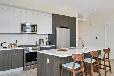 a kitchen with a white counter top and wooden chairs at Lofted Living | Espadin LoHi in Denver