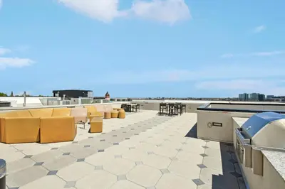 a patio with yellow chairs and tables on a roof at Rosé All Day | Espadin LoHi in Denver