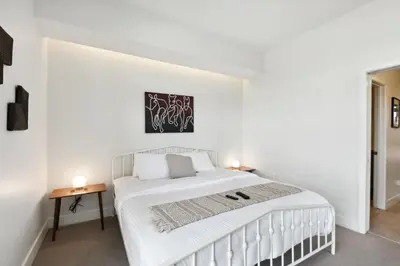a white bedroom with a white bed and two tables at Rosé All Day | Espadin LoHi in Denver