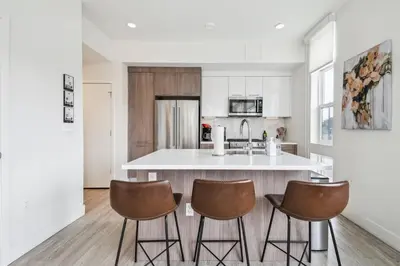 a kitchen with a white counter and three bar stools at Highline Hideaway | Espadin LoHi in Denver