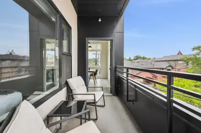 a balcony with two chairs and a bed and windows at Highline Hideaway | Espadin LoHi in Denver