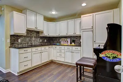a kitchen with white cabinets and a wooden floor at Lakeview - Gameroom - Pool Table in Henderson