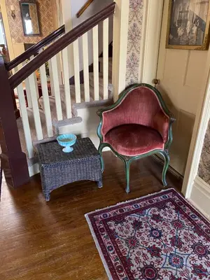 a staircase with a chair and a table and a rug at Pansy’s Parlor Bed & Breakfast in Golden
