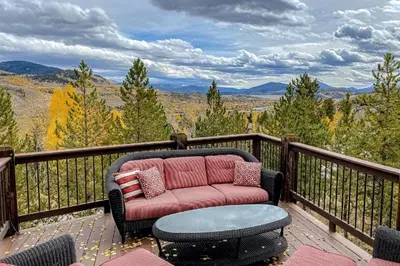 a couch on a deck with a view of the mountains at CoCo Chalet in Silverthorne