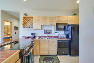 a kitchen with wooden cabinets and a stainless steel refrigerator at Cozy Condo with Balcony and Mtn Views in Silverthorne in Silverthorne
