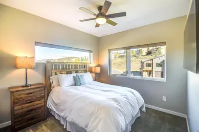 a bedroom with a bed with a ceiling fan and a window at Ski-InandSki-Out Granby Townhouse with Private Hot Tub in Granby