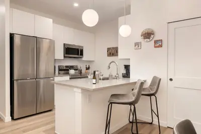 a kitchen with a stainless steel refrigerator and two bar stools at New Condo! Skiboard Winter Park Shuttle in Fraser