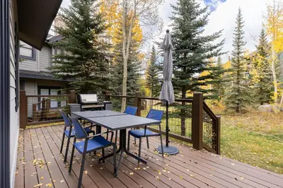 a wooden deck with a table and chairs and an umbrella at 1952 Northstar townhouse in Keystone
