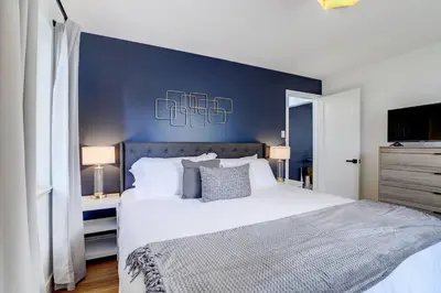 a bedroom with a large bed with a blue wall at 3 Min Walk To Olde Town! Hot Tub, Fire Pit, Games! in Arvada