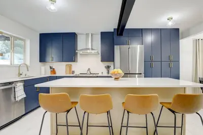 a kitchen with blue cabinets and a kitchen island with chairs at 3 Min Walk To Olde Town! Hot Tub, Fire Pit, Games! in Arvada